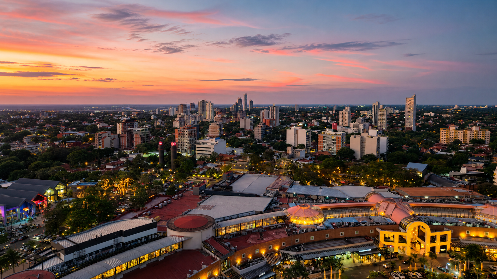 Vista panorámica de Asunción al atardecer con edificios, luces urbanas y cielo rosado